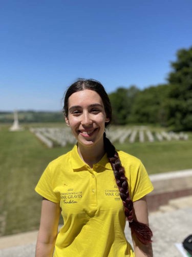 Sophia poses in a yellow CWGF polo shirt in front of the graves at the Thiepval Memorial