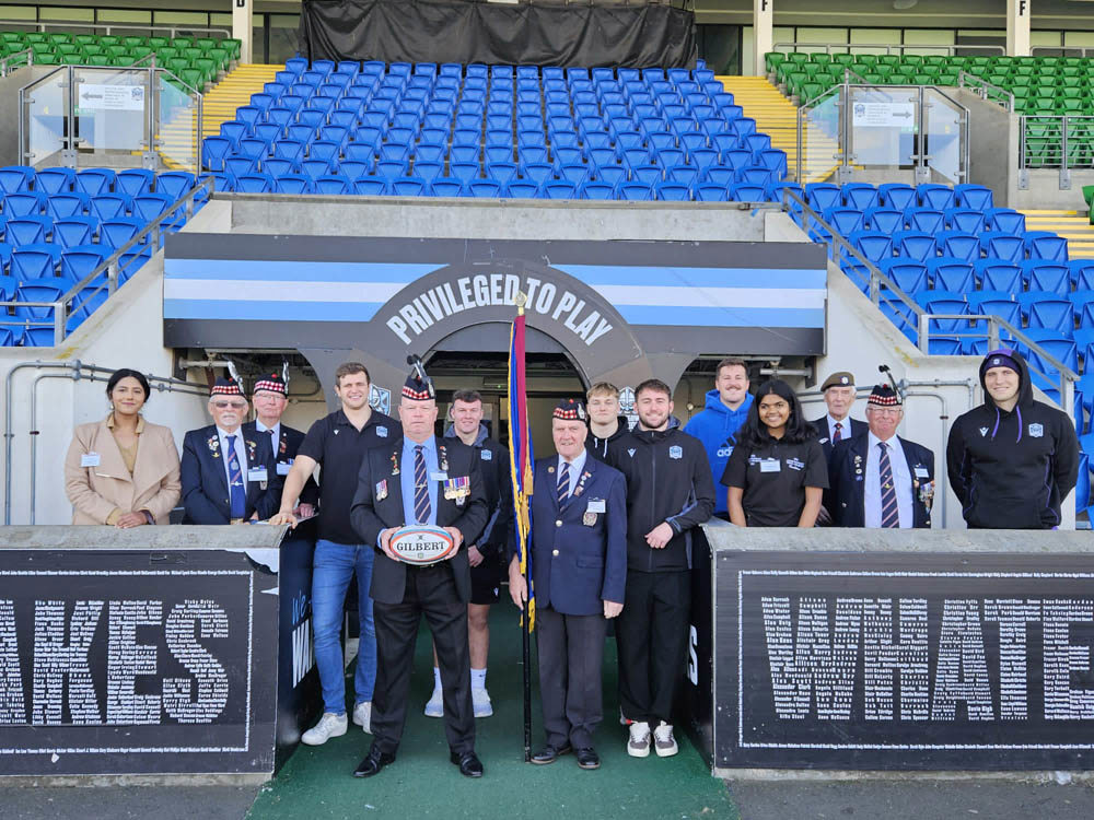 Veterans, a uni student, and a CWGC PEC posing with members of the Glasgow Warriors rugby team in their stadium.