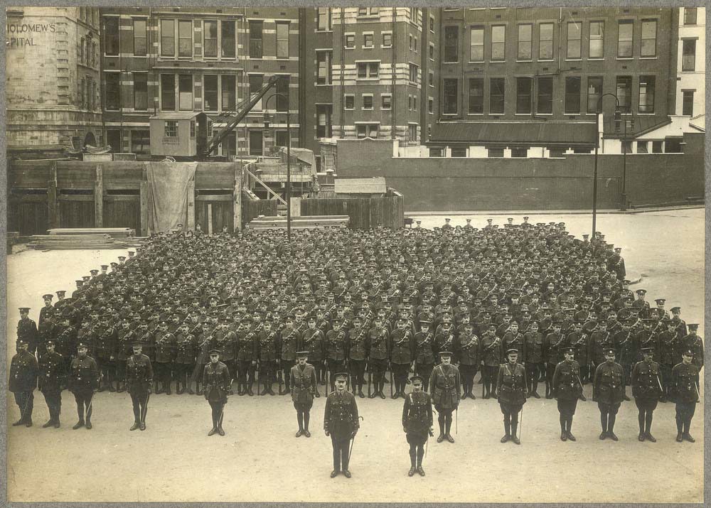 Men of the Post Office Regiment arrayed in parade ground foundation at some point in the First World War. They are standing in a yard somewhere in London.