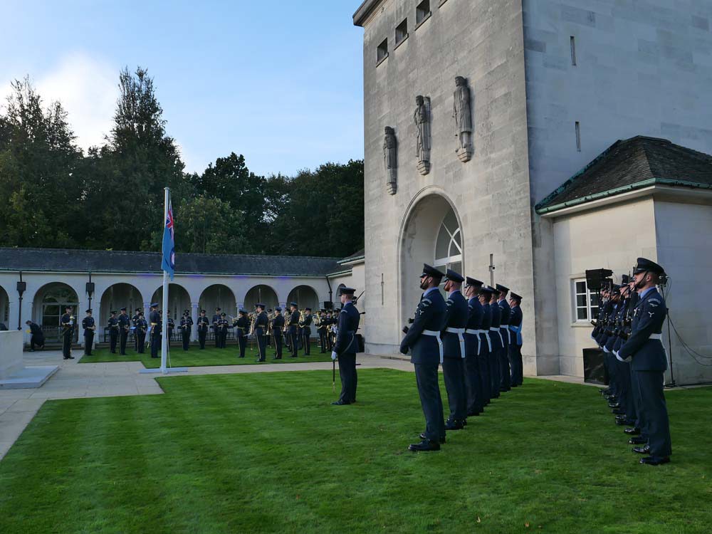 A group of Airmen from the RAAF hold a ceremony at the Runnymede Memorial. The airmen air in grey/blue dress uniforms and arrayed in formation.