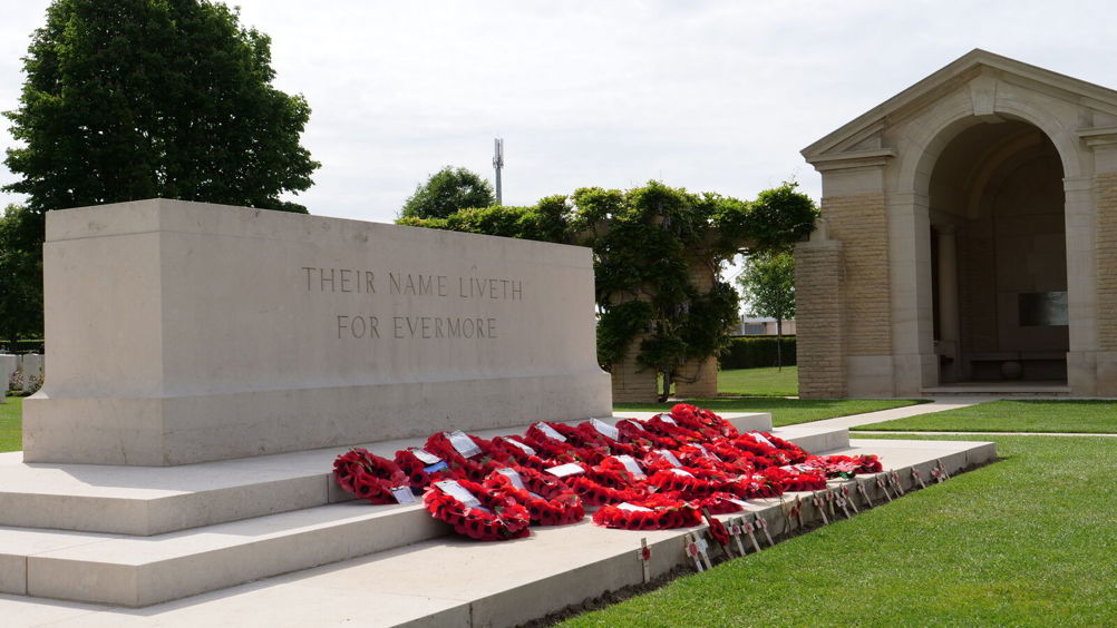 Red poppy wreaths laid on a CWGC Stone of Remembrance.