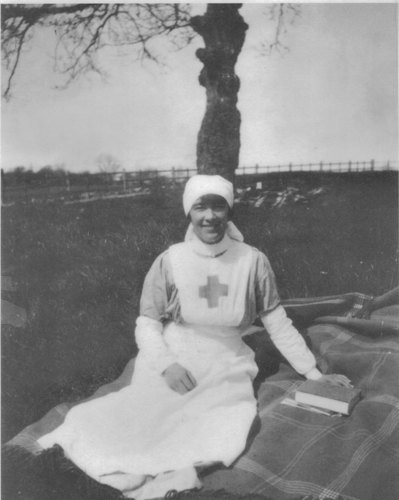 Nurse Kathleen Adele Brennan poses in her nurse's uniform on a picnic blanket in front of a tree.