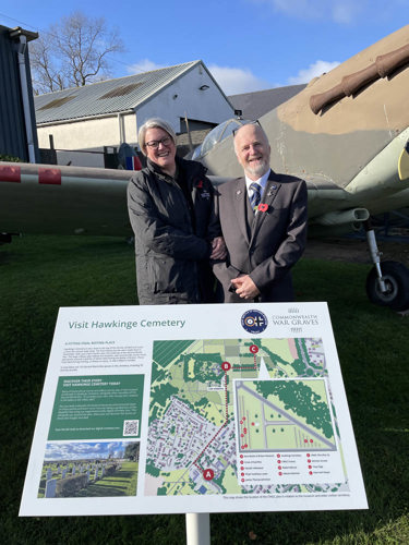 CWGF PEC Sarah Nathaniel and Museum Trustee David Brocklehurst pose behind a new Hakwinge Cemetery information panel in front of a replica Spitfire aircraft.