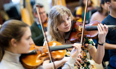 Purcell School musicians playing violins as part of an ensemble.