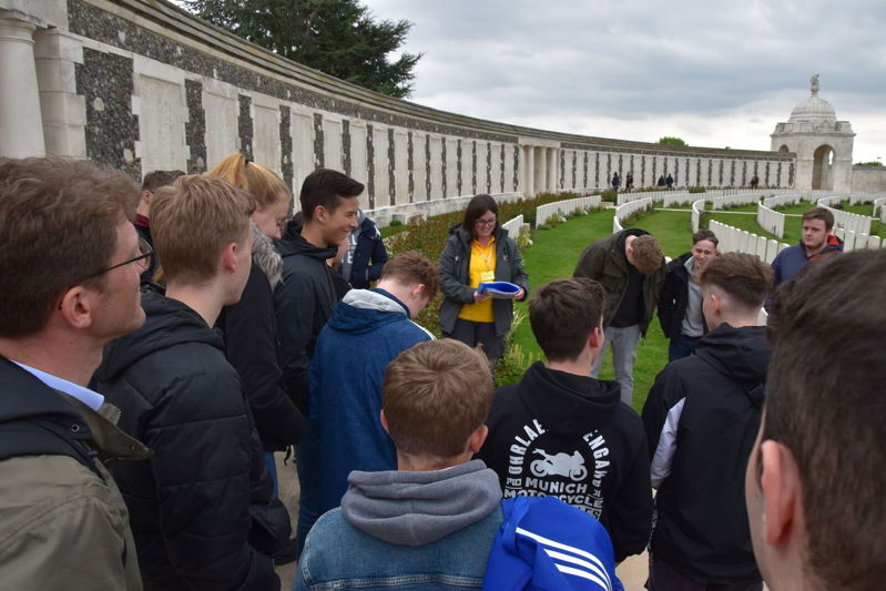 A CWGF tour guide laughs with a group of young guests at Tyne Cot Cemetery.