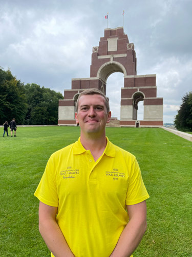 CWGF guide Alex stands in front of the Thiepval Memorial in France. Alex is wearing a bright yellow polo shirt.