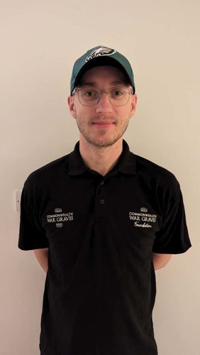 Portrait of David Edwards. He is wearing a black polo shirt, rounded thin frame glasses and a black polo shirt.