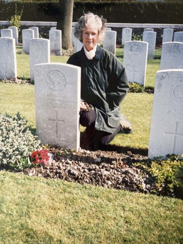 Gill kneels at Captain Hay's war grave at Poperinghe New Military Cemetery