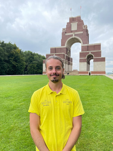 CWGF Guide Remy Gossart standing in front of the Thiepval Memorial. Remi is wearing a bright yellow polo shirt and dark trousers.