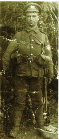 A slightly damaged, green-tinted photography of Clarence Holmes. He is a WW1-era Britihs soldier wearing his uniform.