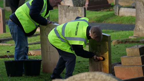 Eyes On, Hands On volunteers clean a headstone.
