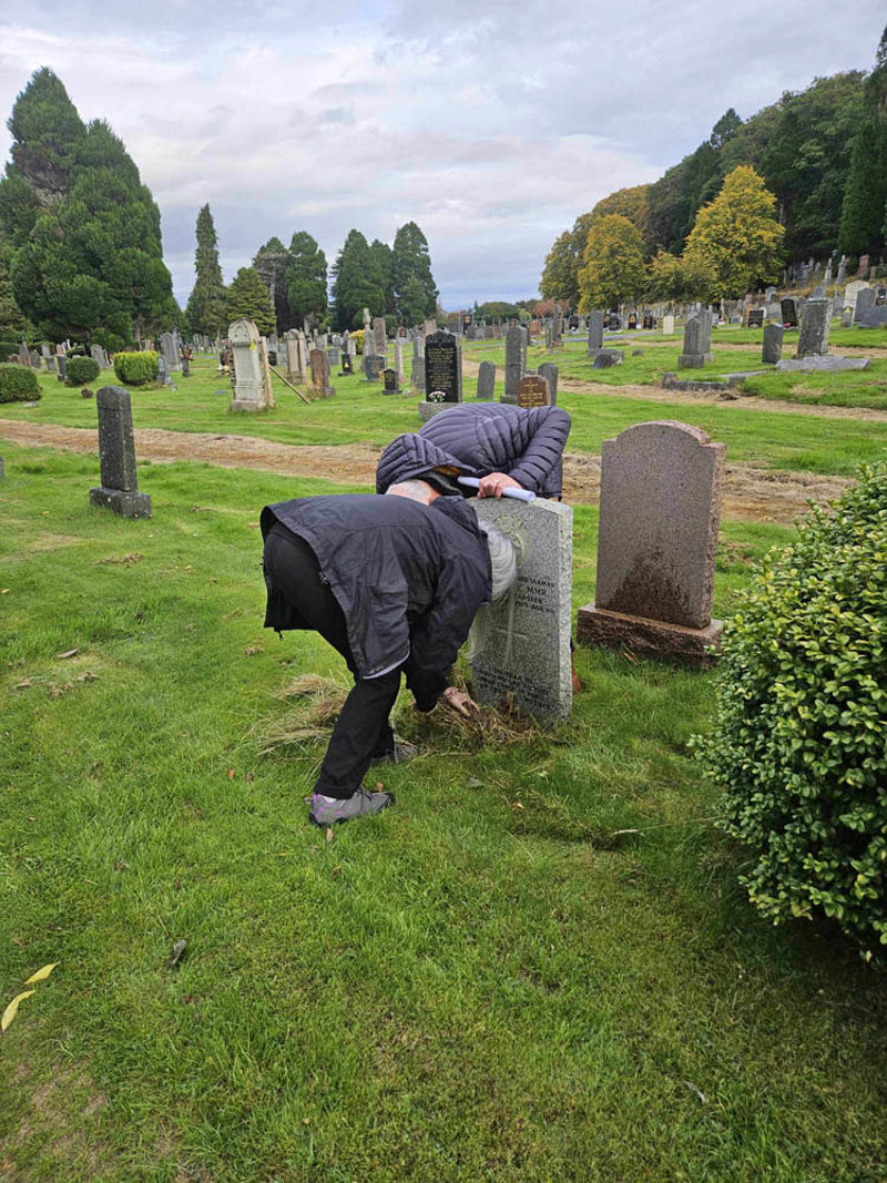 CWGC Eyes On, Hands On volunteers inspecting a CWGC headstone